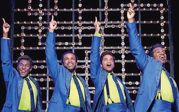 Performers in blue suits on stage during "Beautiful: The Carole King Musical.