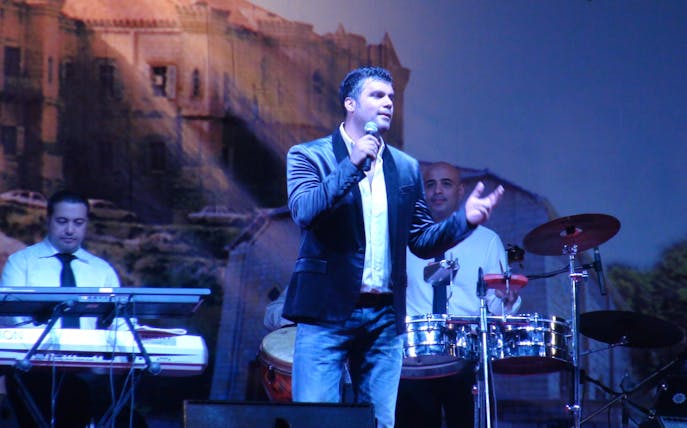 Singer performing on stage with musicians during Fares Karam & Maya Diab concert.