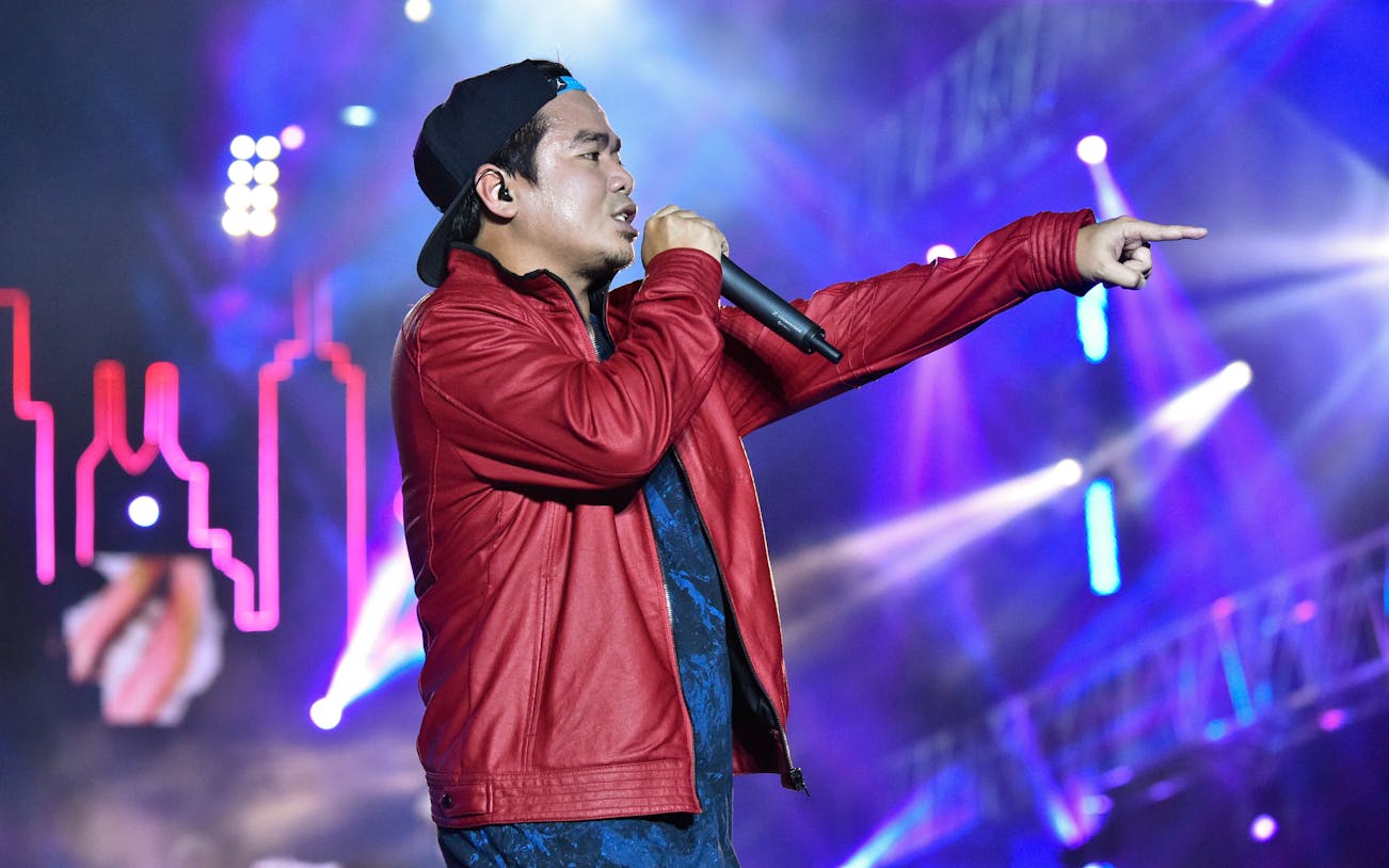 Performer on stage at TAG FEST with vibrant lights in the background.