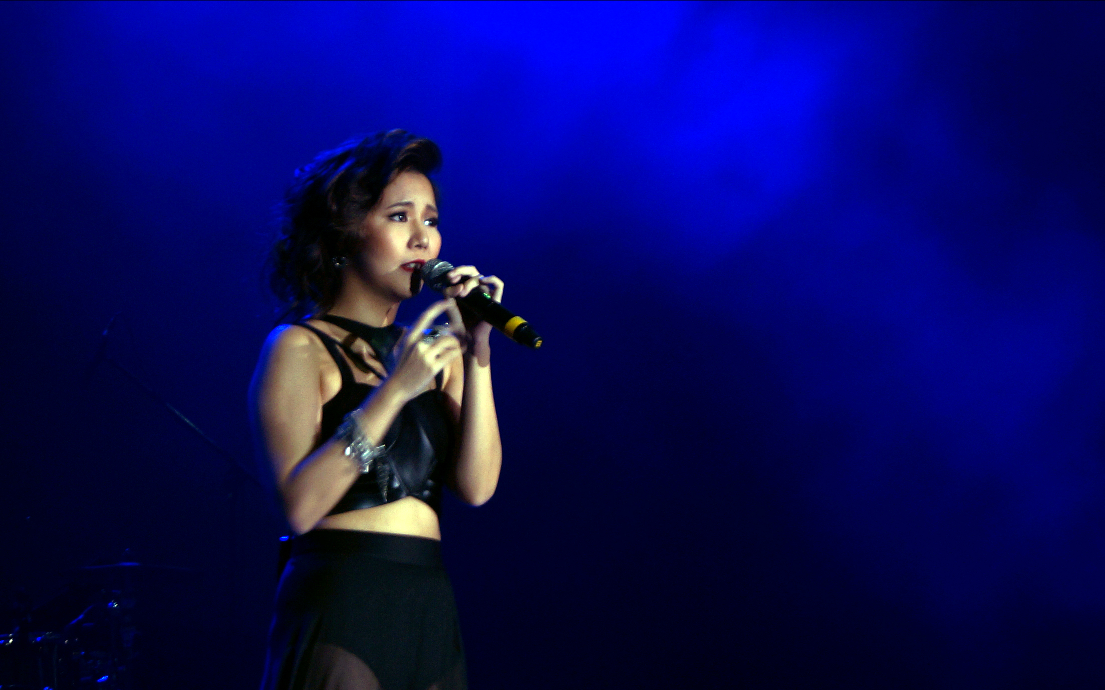 Singer performing on stage at TAG FEST with blue lighting.