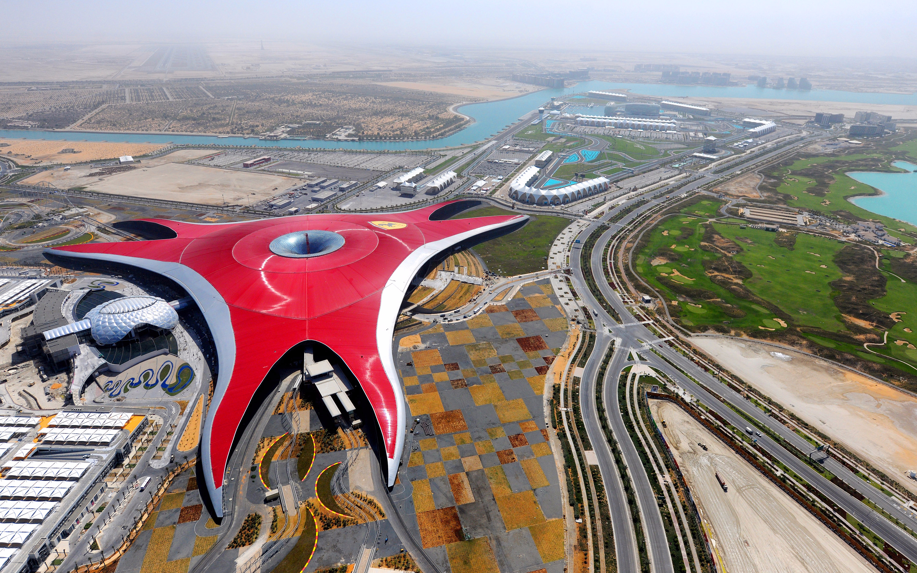 Aerial view of Ferrari World in Abu Dhabi, featuring its iconic red roof, seen during a Seawings Seaplane Tour.