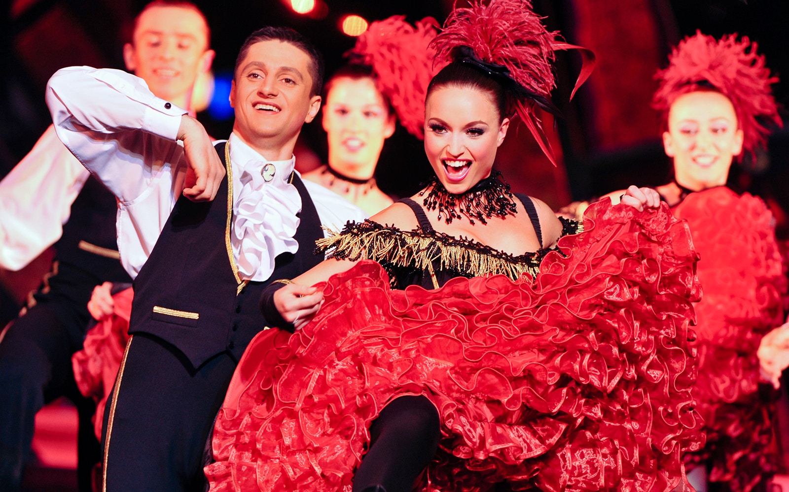 Performers in vibrant costumes dancing at Paradis Latin, Paris New Year's show.