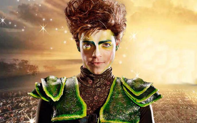 Performer in Peter Pan costume with a glowing background.
