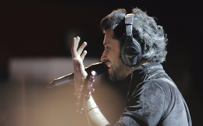 Singer performing live with headphones and microphone, Atif Aslam concert.