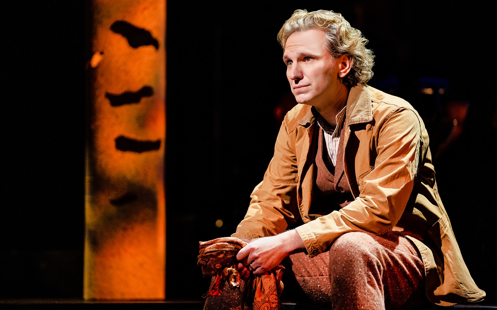 Man in period costume sitting on stage during "Into The Woods" performance.