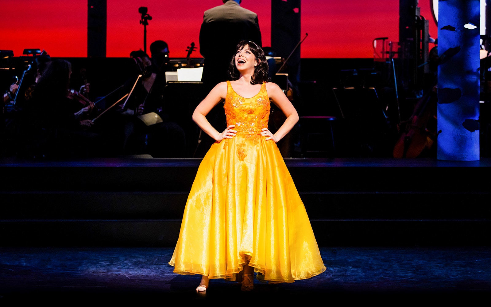 Performer in a yellow dress on stage during "Into The Woods" musical.