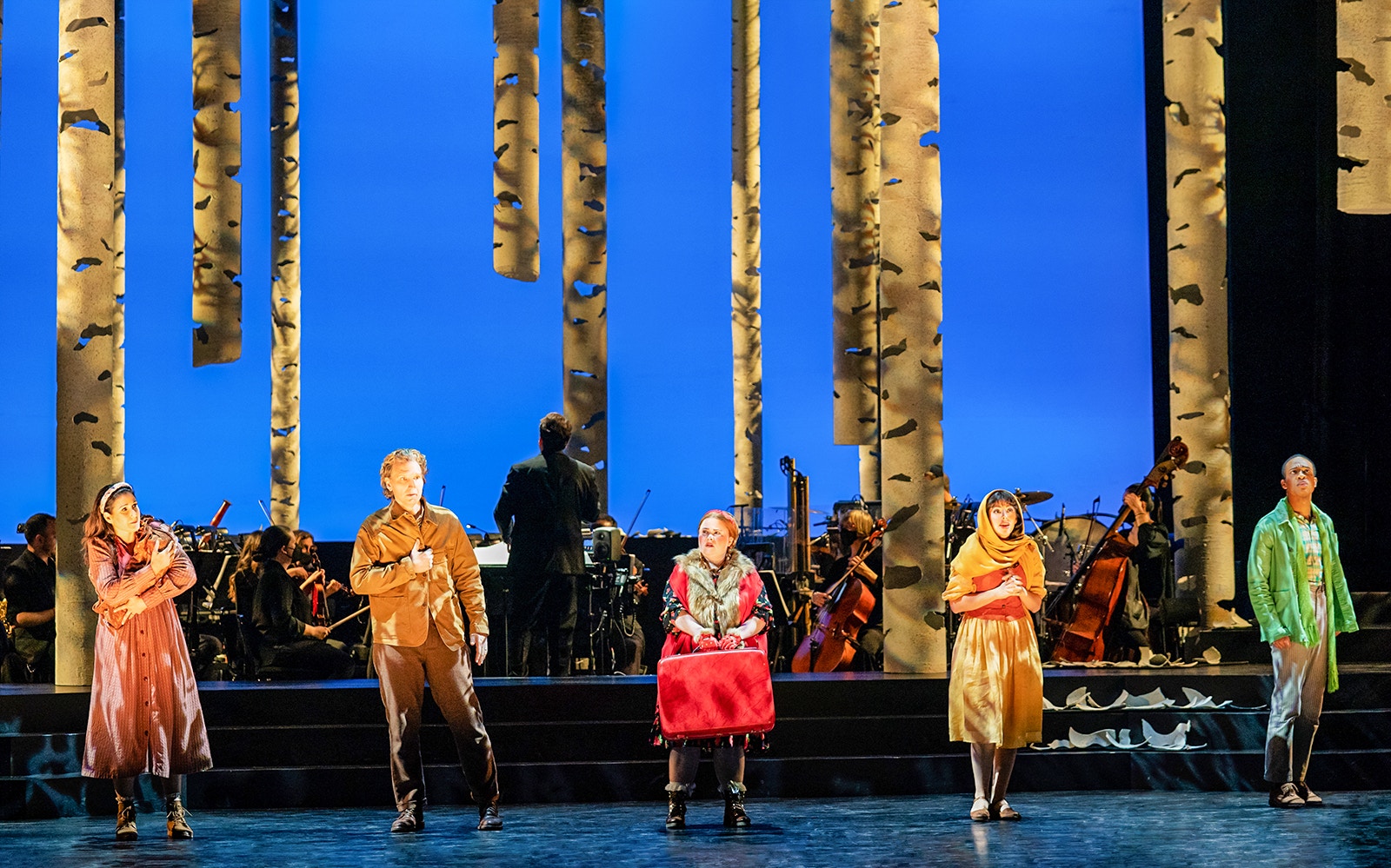 Stage performance of "Into The Woods" with actors in front of a forest backdrop.