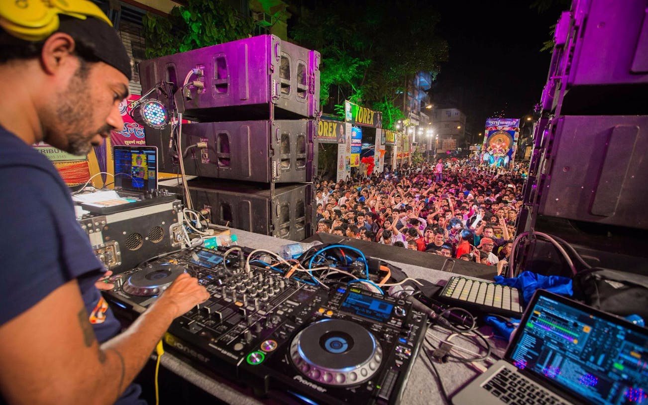 DJ performing live set at outdoor concert in Dubai with large crowd.