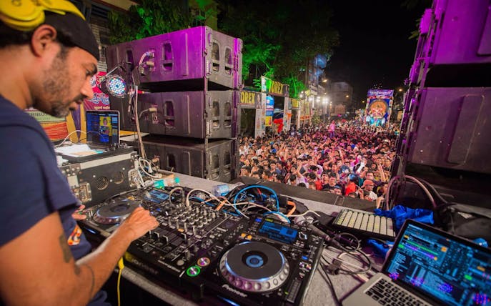 DJ performing live set at outdoor concert in Dubai with large crowd.