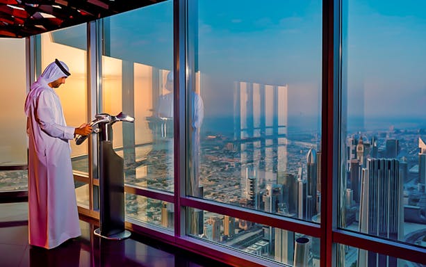 Man viewing Dubai skyline from Burj Khalifa observation deck during city tour.